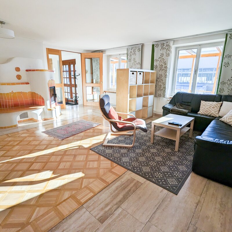 Bright living room with tiled stove & leather sofa – 3-room apartment, short-term rental & temporary housing 1 to 6 months, Graz