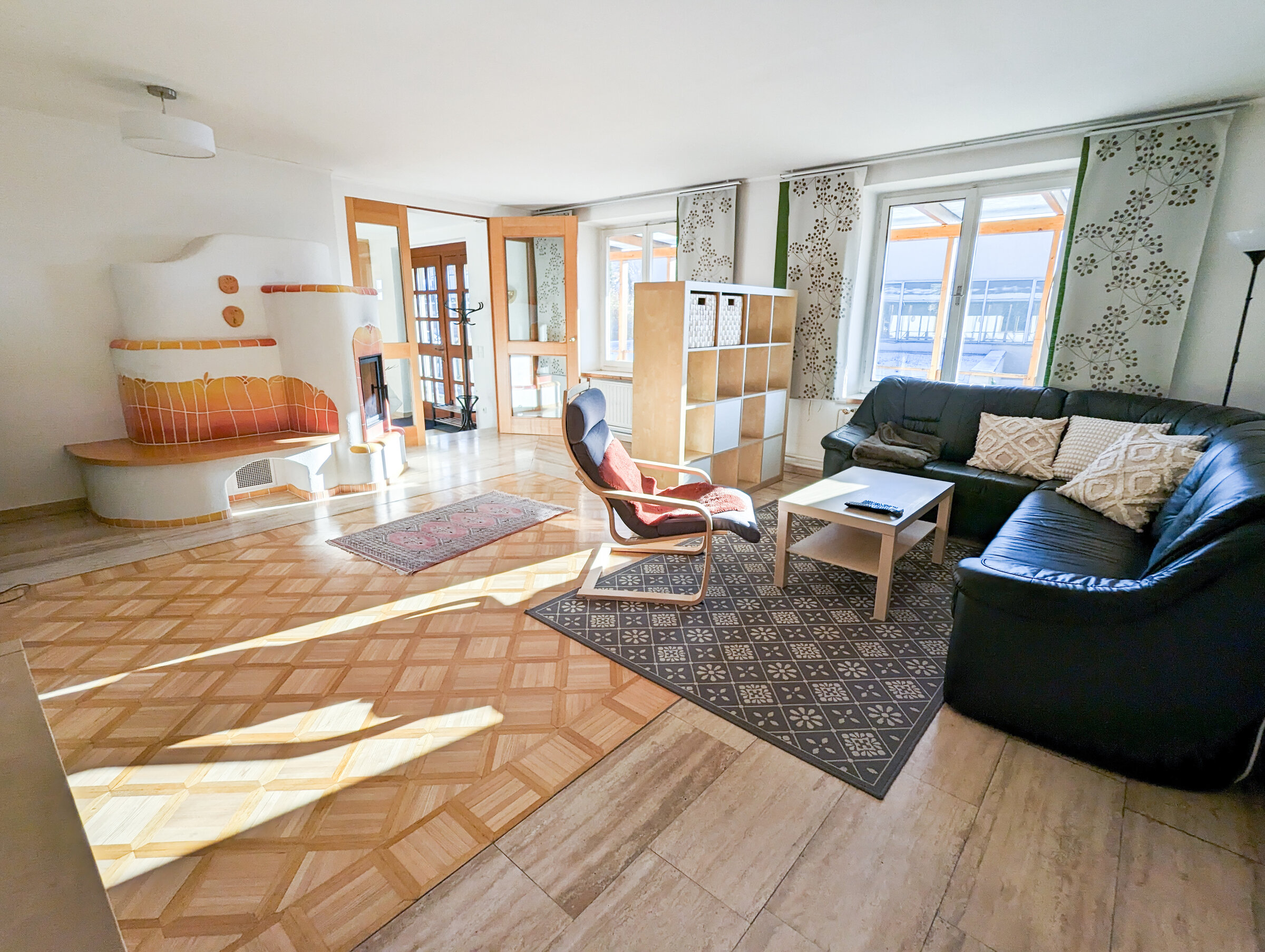 Bright living room with tiled stove & leather sofa – 3-room apartment, short-term rental & temporary housing 1 to 6 months, Graz