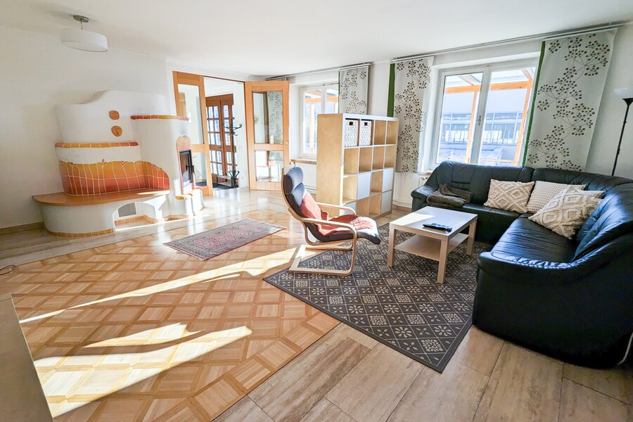 Bright living room with tiled stove & leather sofa – 3-room apartment, short-term rental & temporary housing 1 to 6 months, Graz