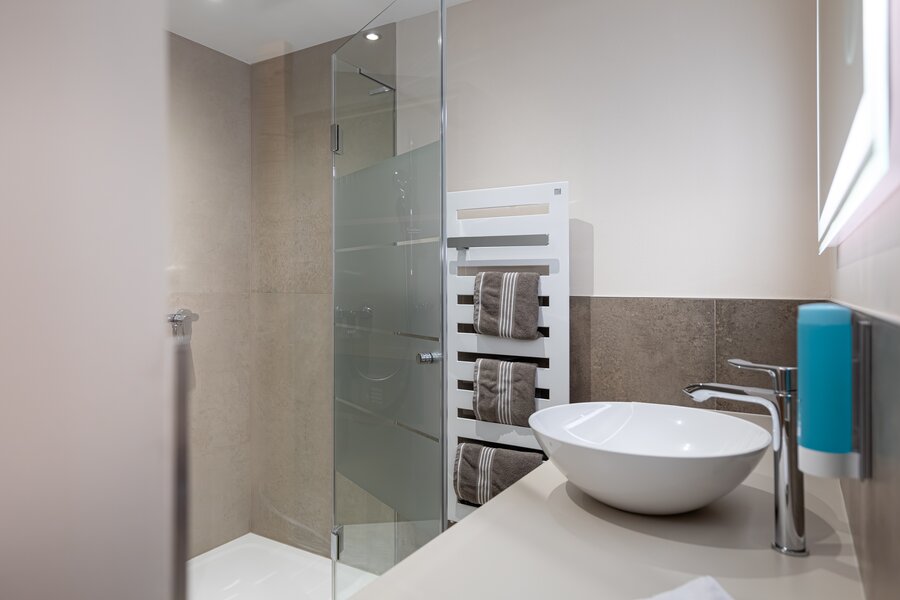 Modern bathroom with glass shower & towel radiator – 1-room apartment, short-term rental Salzburg, temporary housing for 1 to 6 months
