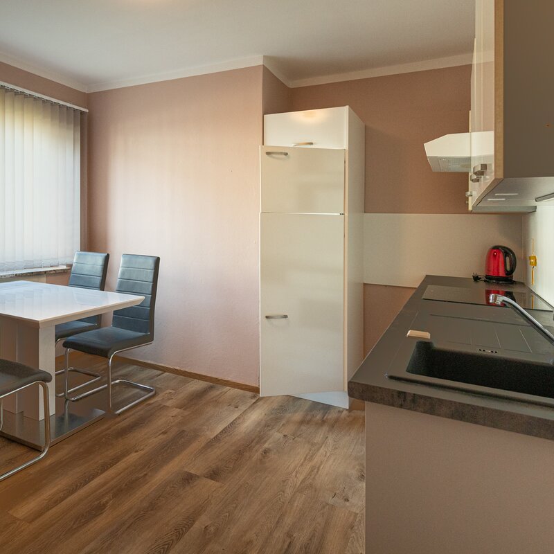 mit Esstisch, Kühlschrank, Ofden, Herd, Wasserkocher sowie Bessteck, Teller und Gläser