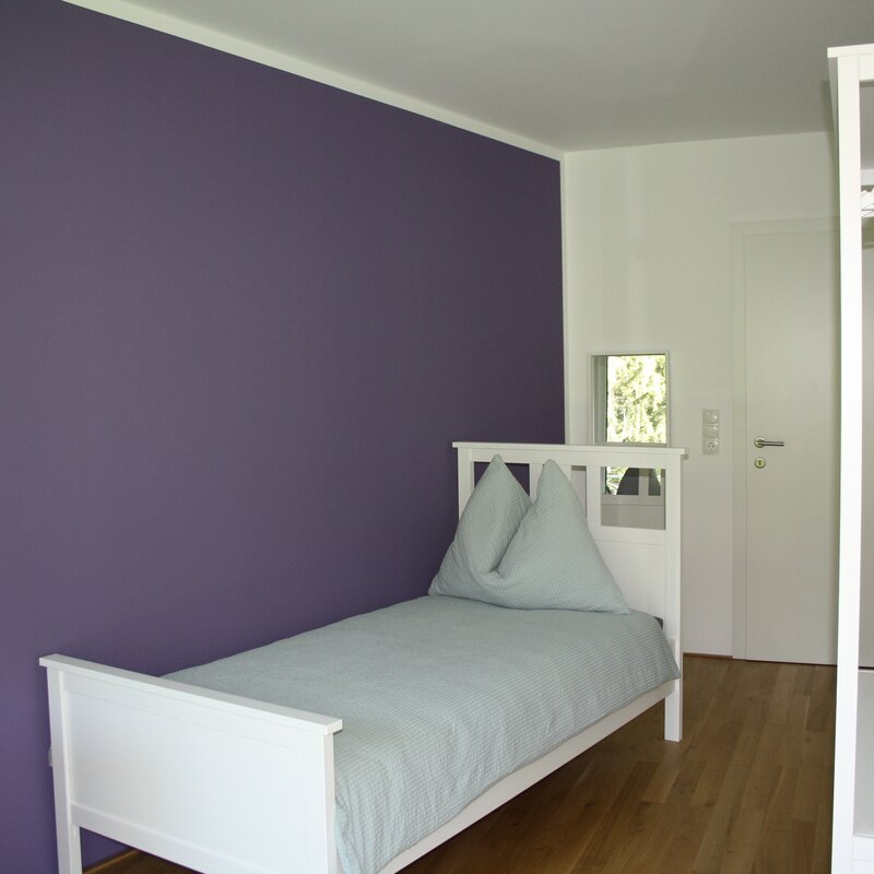 Bright room with single bed & purple accent wall – 4-room apt, short-term rental Innsbruck, temporary housing for 1 to 6 months