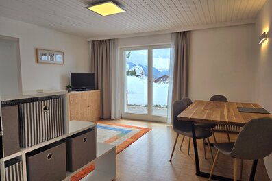 Bright living area with wooden table & mountain view – 2-room apartment, short-term rental Patsch, temporary housing for 1 to 6 months