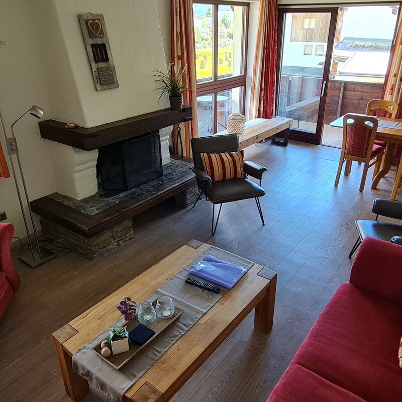 Wohnzimmer mit offenen Kamin und zugang zum Balkon | © Kazza