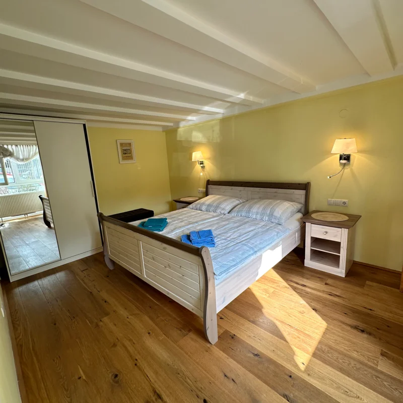 Das Schlafzimmer ist ausgestattet mit einem 2m x 1,80m Bett, einem Kasten mit Spiegel und Nachttischen