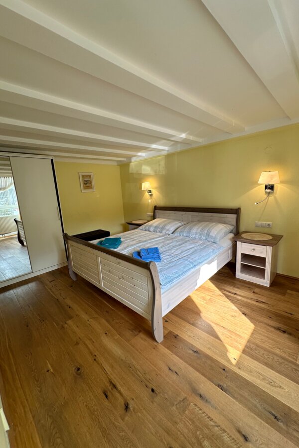 Das Schlafzimmer ist ausgestattet mit einem 2m x 1,80m Bett, einem Kasten mit Spiegel und Nachttischen