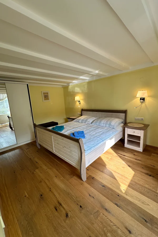 Das Schlafzimmer ist ausgestattet mit einem 2m x 1,80m Bett, einem Kasten mit Spiegel und Nachttischen