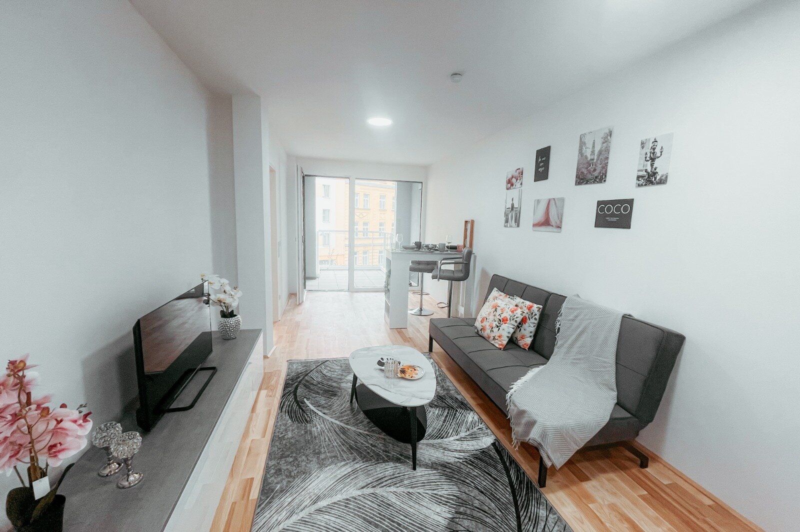 Bar table with chairs, modern dresser, flat-screen TV, rug, and coffee table, carefully selected furniture decoration that invites relaxation and enjoyment. | © All rights reserved