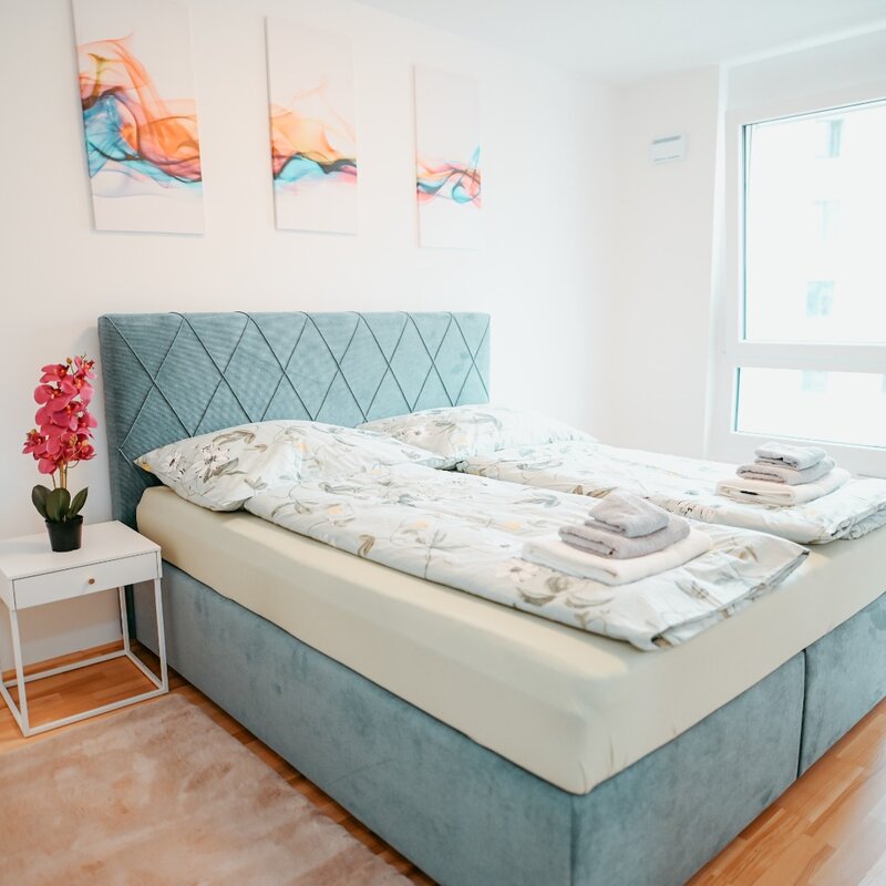Bedroom with a large bed, wardrobe, two rugs, closet, two bedside tables, and a lamp. | © All rights reserved