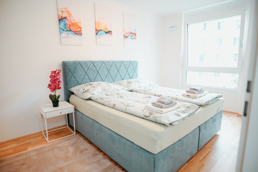 Bedroom with a large bed, wardrobe, two rugs, closet, two bedside tables, and a lamp. | © All rights reserved