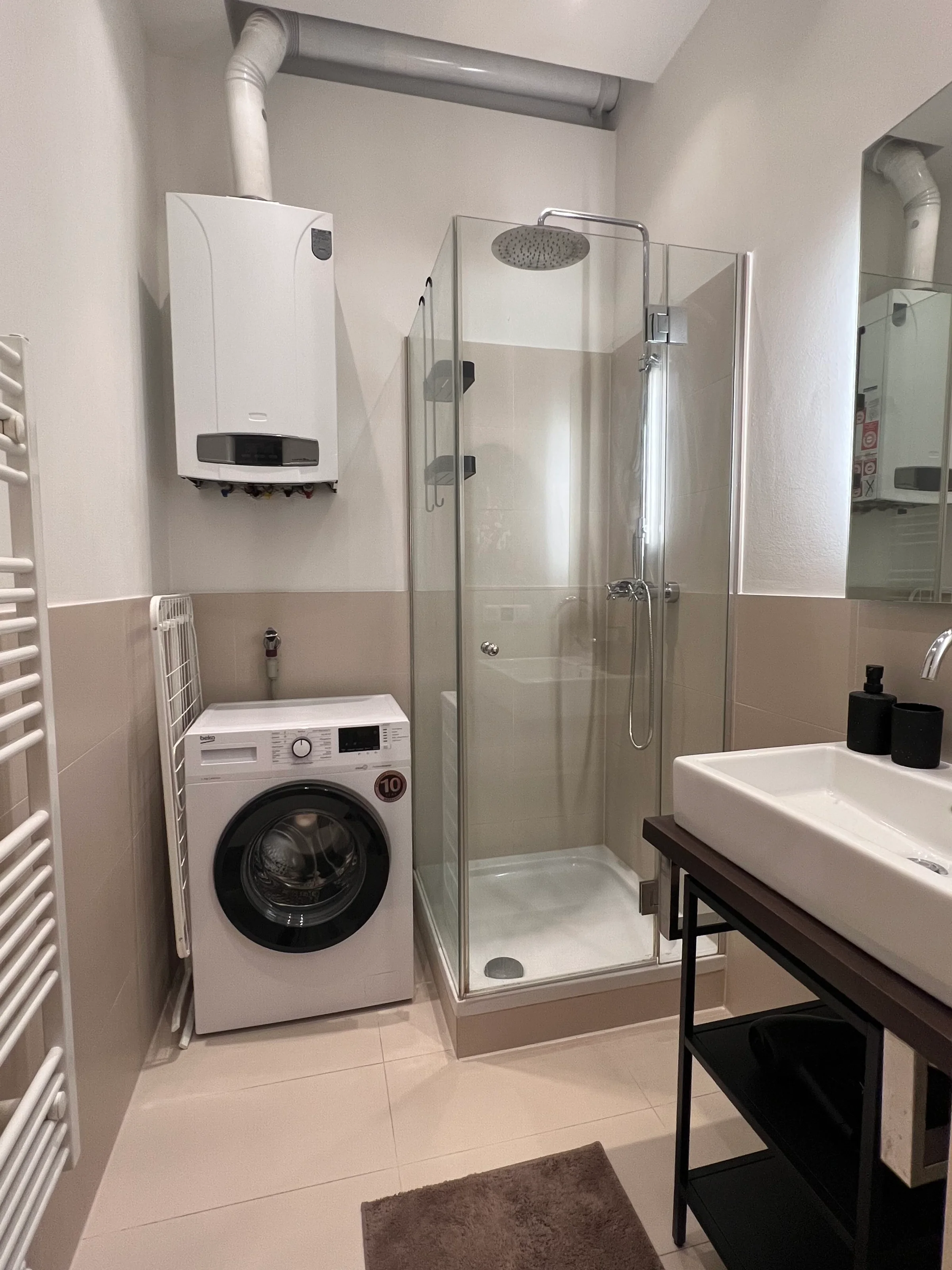 Badezimmer mit Regendusche, Waschmaschine, Wäschespinne und Föhn