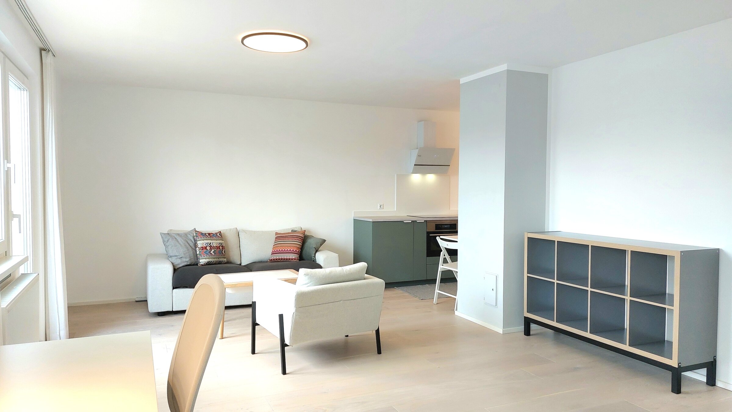 Wohnzimmer mit Arbreitsplatz und angeschlossener Küche