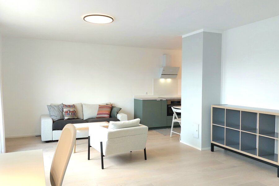 Wohnzimmer mit Arbreitsplatz und angeschlossener Küche