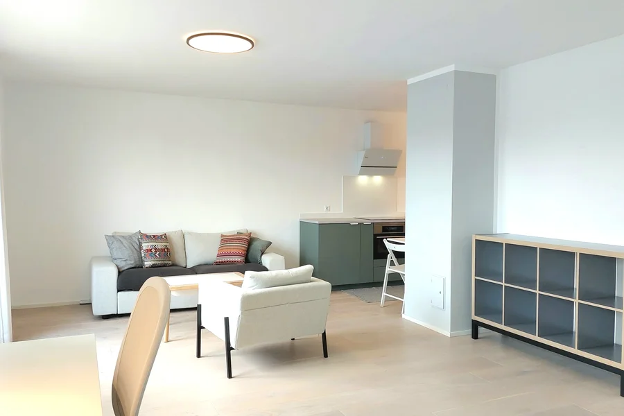 Wohnzimmer mit Arbreitsplatz und angeschlossener Küche