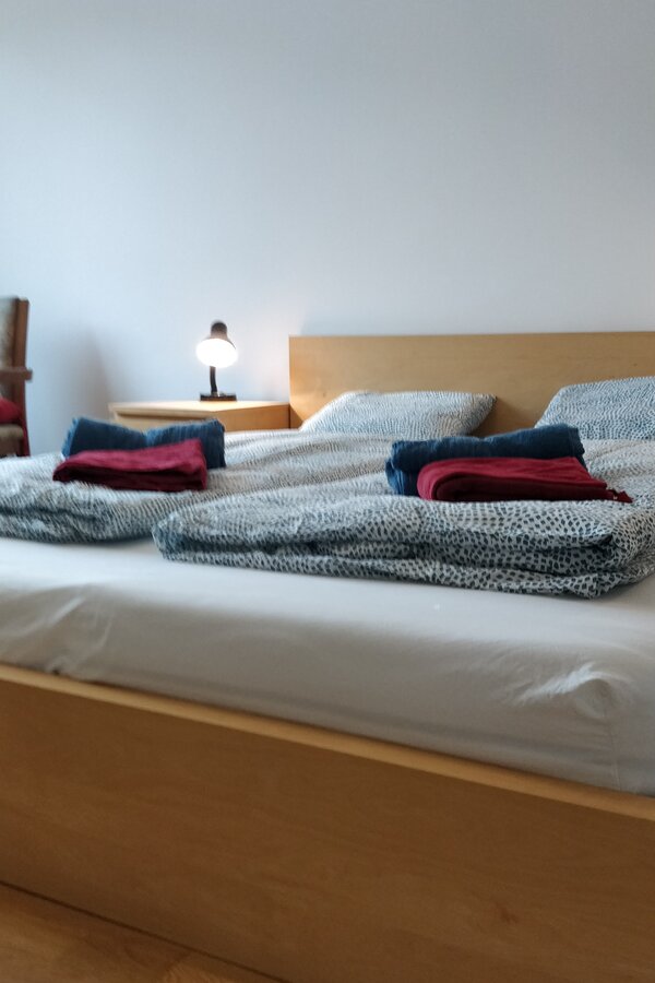 Bright bedroom with double bed & bedside lamp – 1-room apartment for short-term rental & temporary housing for 1 to 6 months in Vienna