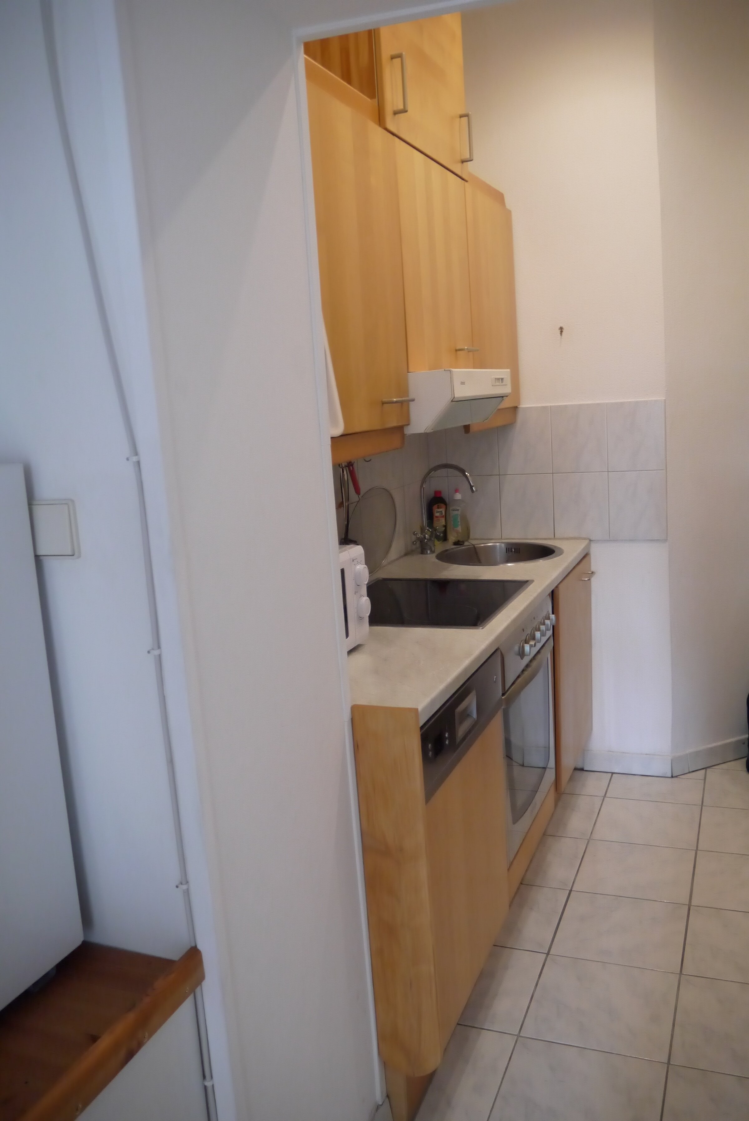 Küche vom Vorraum betrachtet mit Mikrowelle, Geschirrspüler, Spüle und Herd