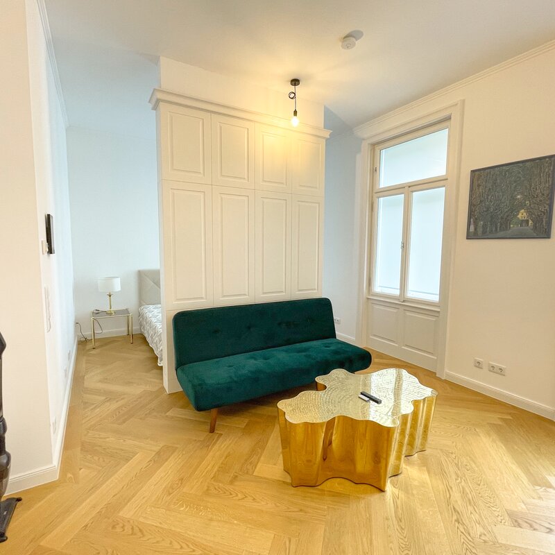 Wohnzimmer mit Küche und dahinterliegendem Schlafzimmer