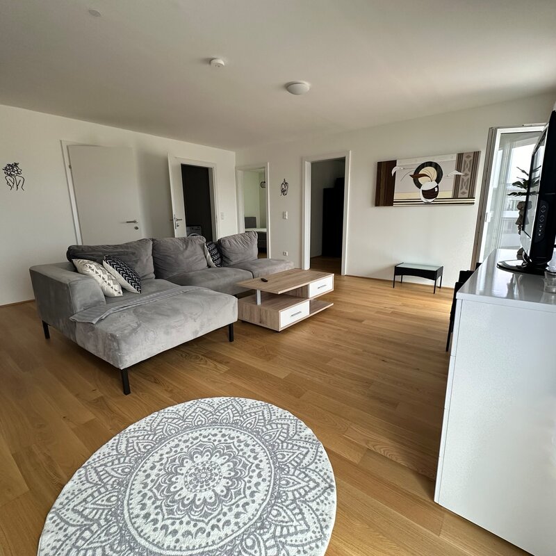 Bright living room with wood floor & sofa – 3-room apartment for short-term rental & temporary housing for 1 to 6 months in Traun