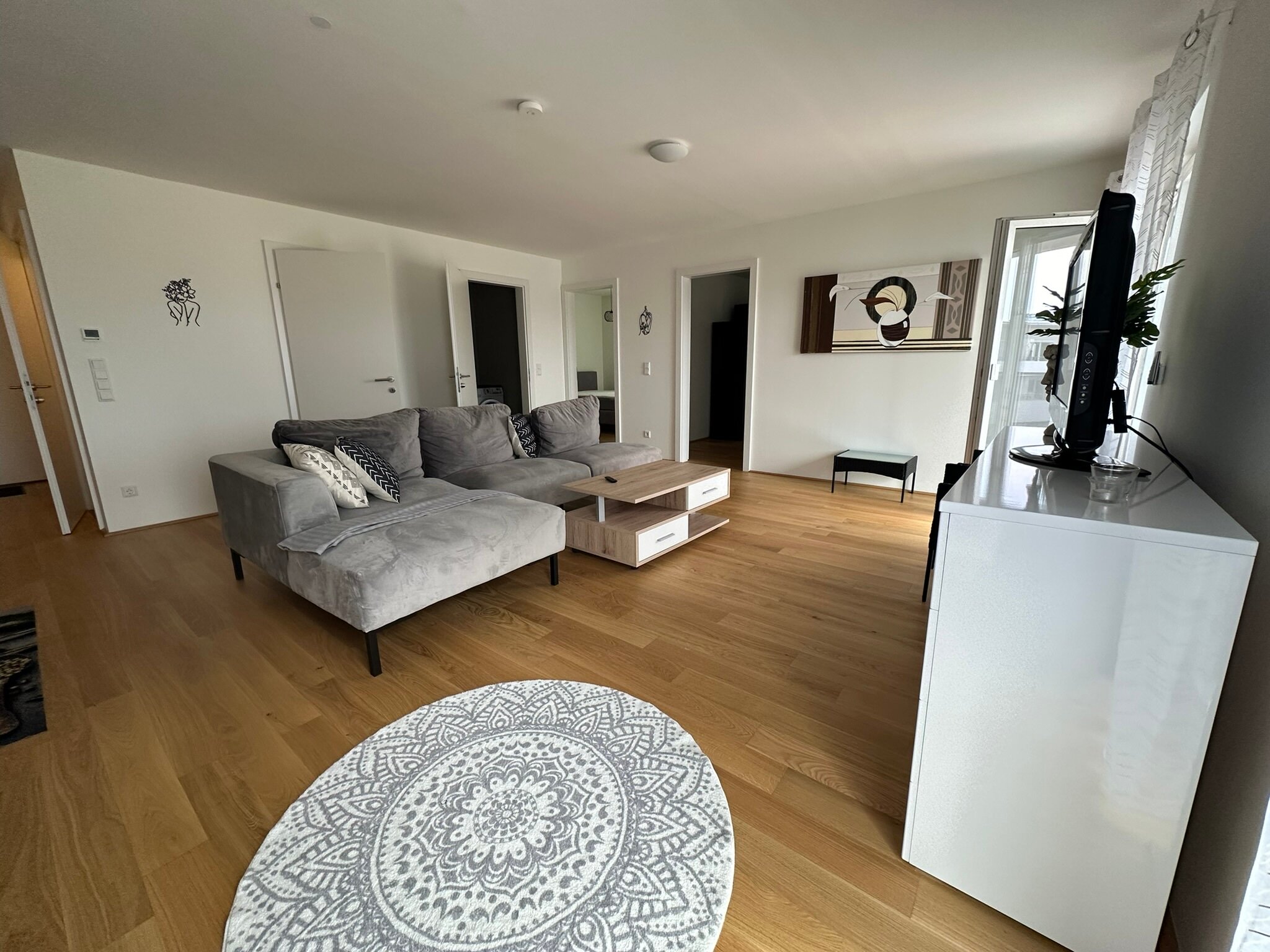 Bright living room with wood floor & sofa – 3-room apartment for short-term rental & temporary housing for 1 to 6 months in Traun