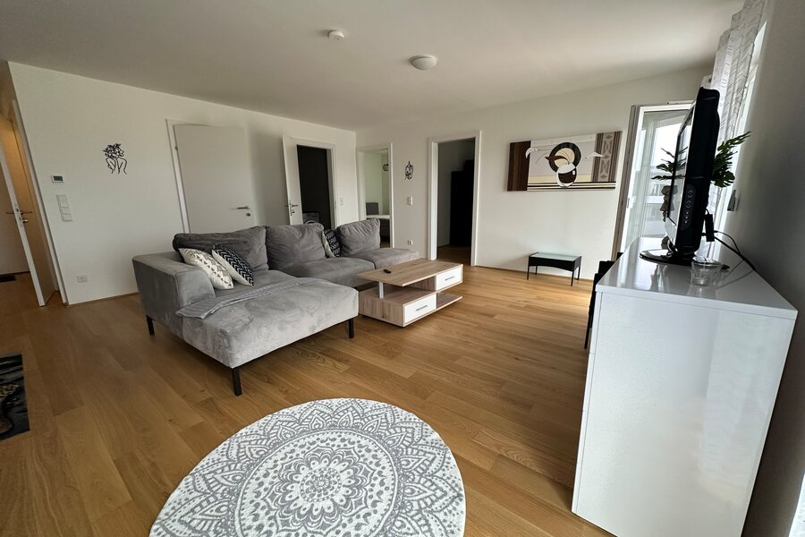 Bright living room with wood floor & sofa – 3-room apartment for short-term rental & temporary housing for 1 to 6 months in Traun