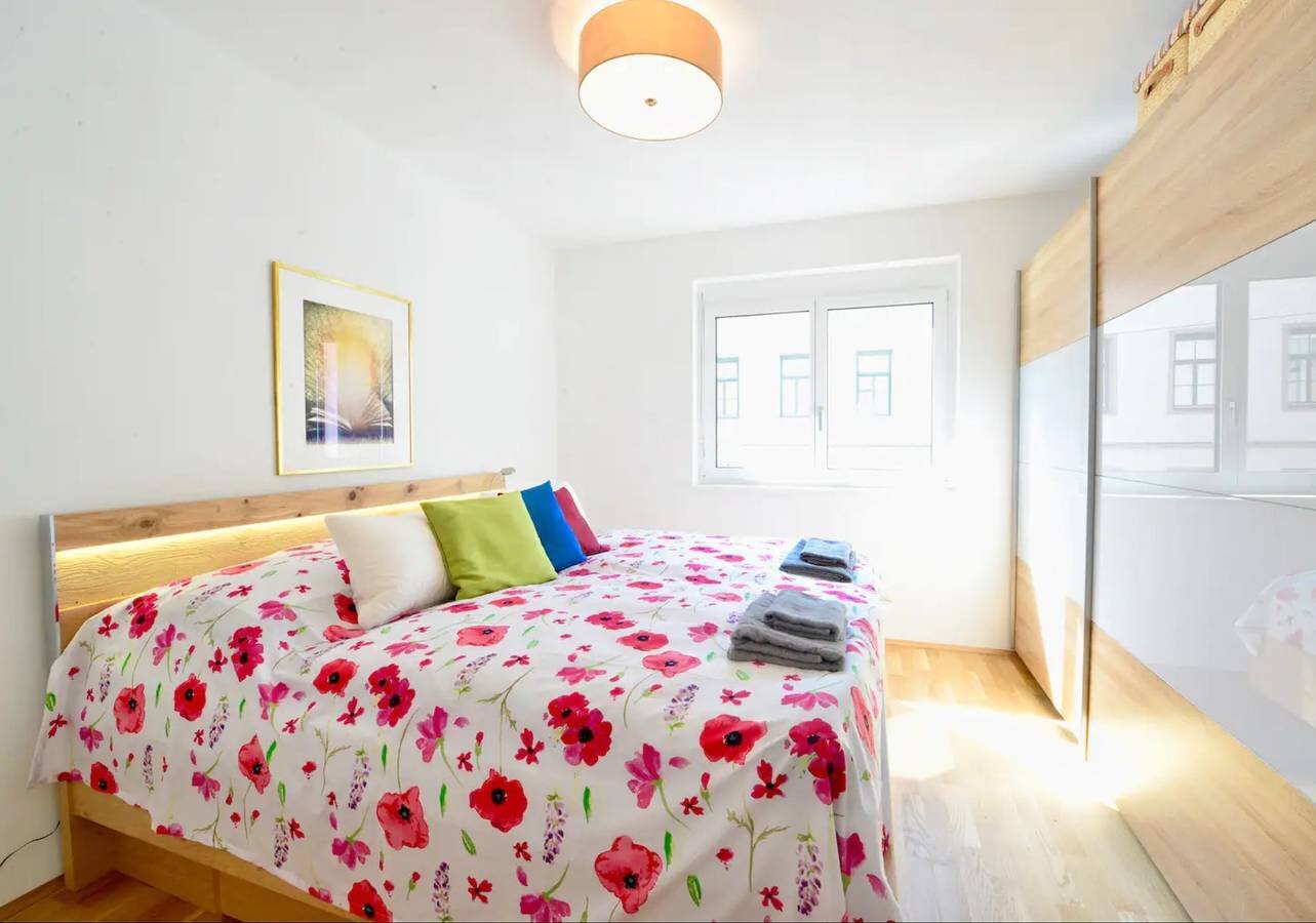 Helles Schlafzimmer mit Blumenbettwäsche & Einbauschrank – 2-Zimmer-Wohnung zur Kurzzeitmiete, Wohnen auf Zeit 1 bis 6 Monate, Wien