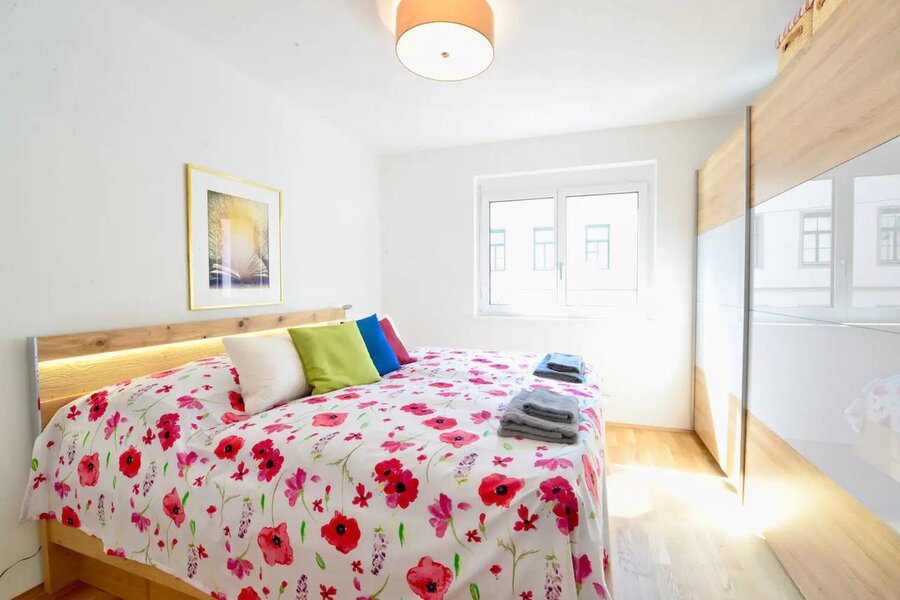 Helles Schlafzimmer mit Blumenbettwäsche & Einbauschrank – 2-Zimmer-Wohnung zur Kurzzeitmiete, Wohnen auf Zeit 1 bis 6 Monate, Wien