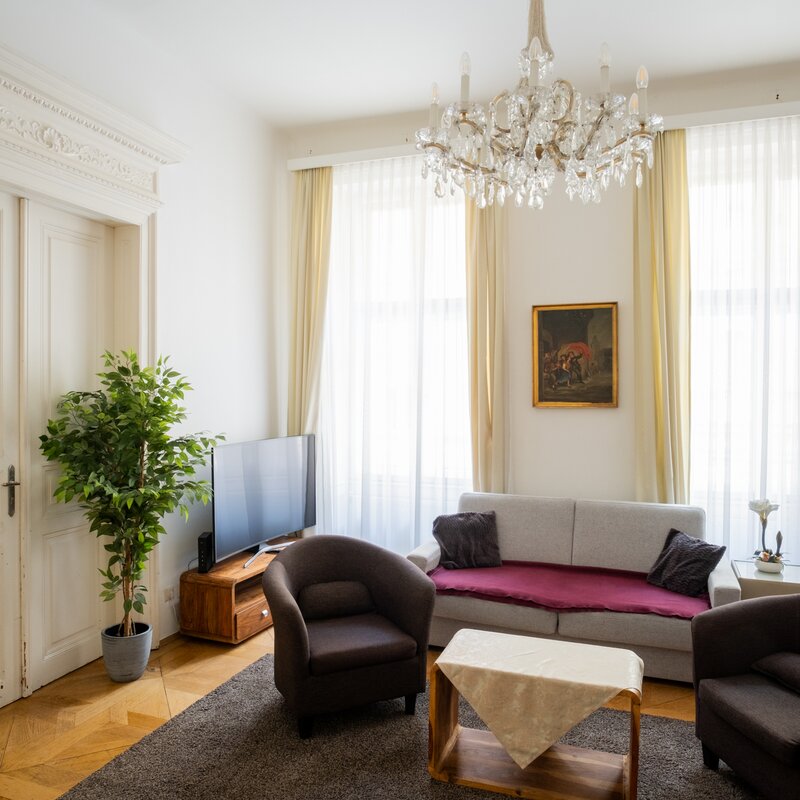 Bright living room with chandelier & stucco – 2-room apt, short-term rental Vienna, temporary housing 1 to 6 months