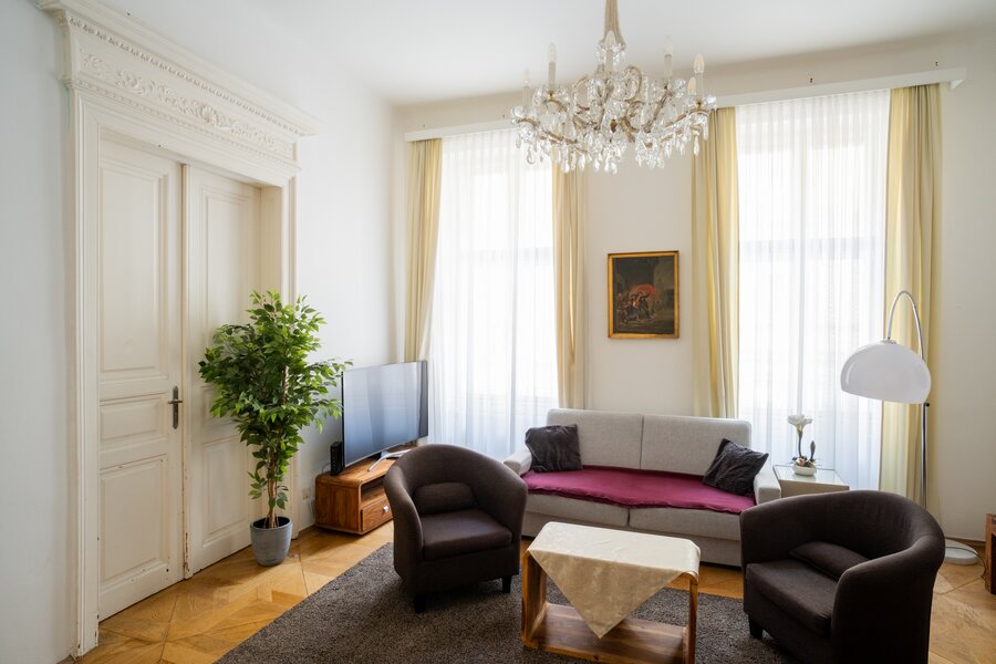 Bright living room with chandelier & stucco – 2-room apt, short-term rental Vienna, temporary housing 1 to 6 months