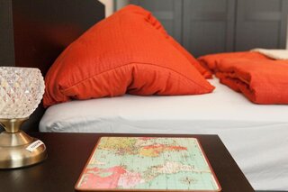 Cozy bedroom with orange pillows & decor – 1-room apartment for short-term rental, temporary housing for 1 to 6 months, Vienna