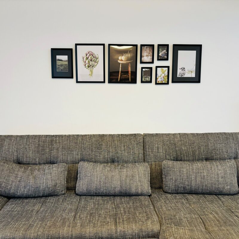Bright living room with sofa & gallery wall – 4-room apartment for short-term rental & temporary housing for 1 to 6 months in Thalheim bei Wels.