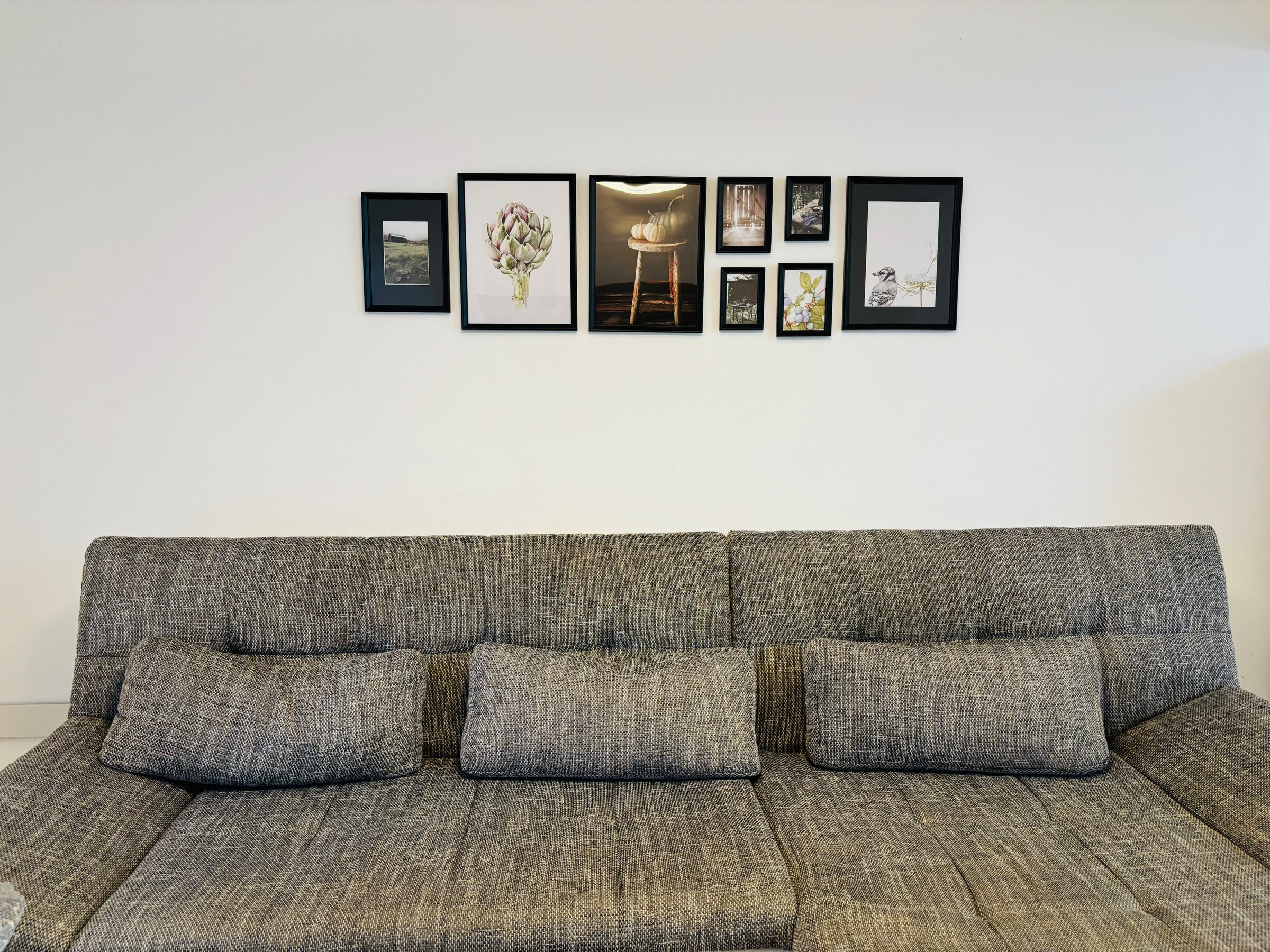 Bright living room with sofa & gallery wall – 4-room apartment for short-term rental & temporary housing for 1 to 6 months in Thalheim bei Wels.