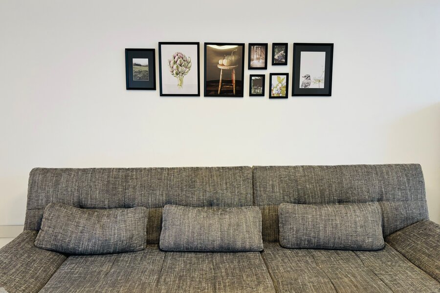 Bright living room with sofa & gallery wall – 4-room apartment for short-term rental & temporary housing for 1 to 6 months in Thalheim bei Wels.