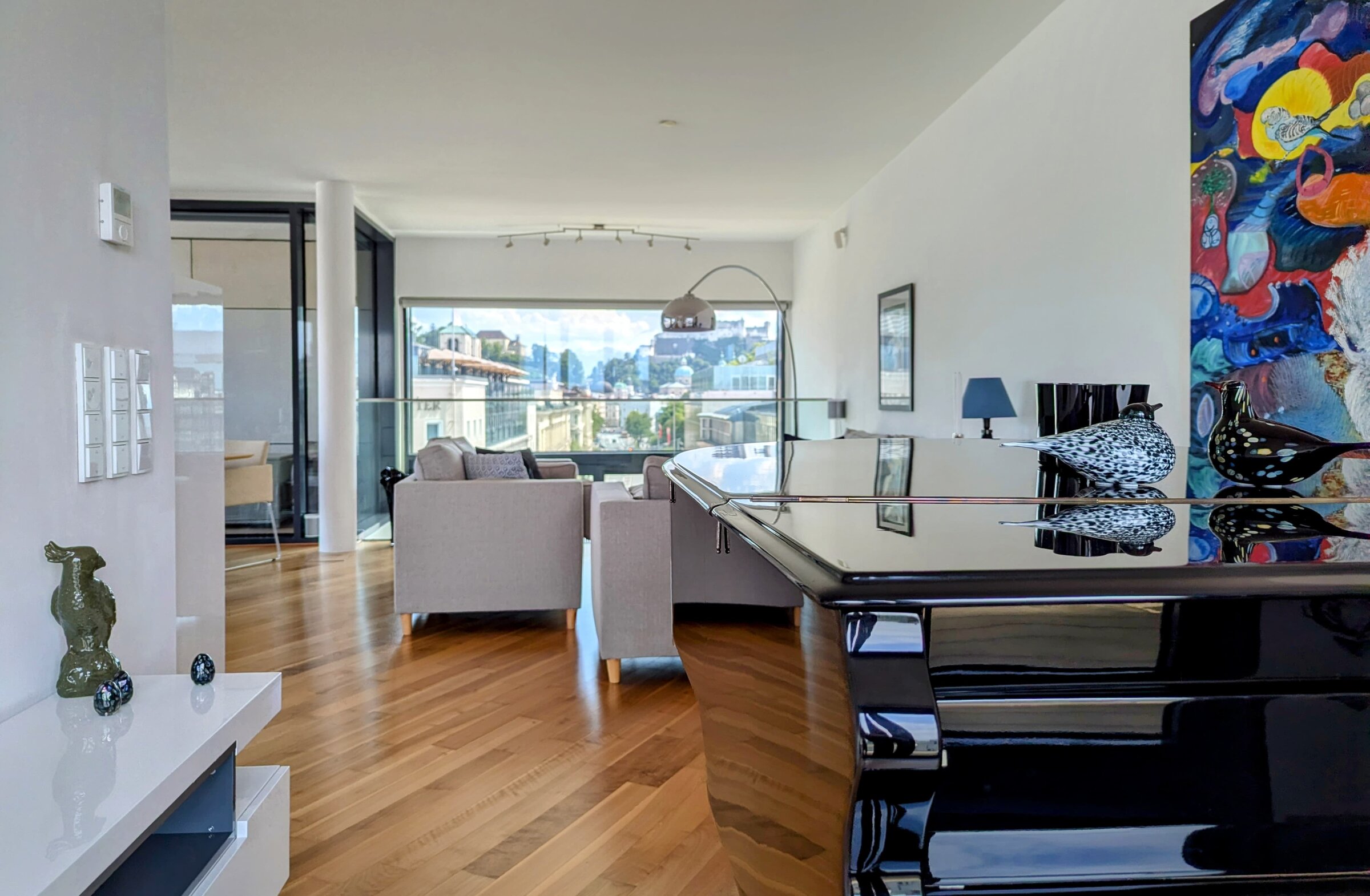 Bright living room with grand piano & panoramic window – 4-room penthouse, short-term rental & temporary housing for 1 to 6 months in Salzburg