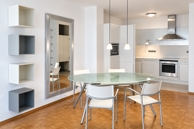 Bright dining area with glass table & open kitchen – 2-room apartment, short-term rental Graz, temporary housing for 1 to 6 months