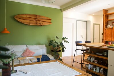 The heart of our apartment – the open-plan living kitchen with a balcony overlooking the courtyard. A modern kitchen island, dining table, and a cozy sofa corner. | © ©laurabell