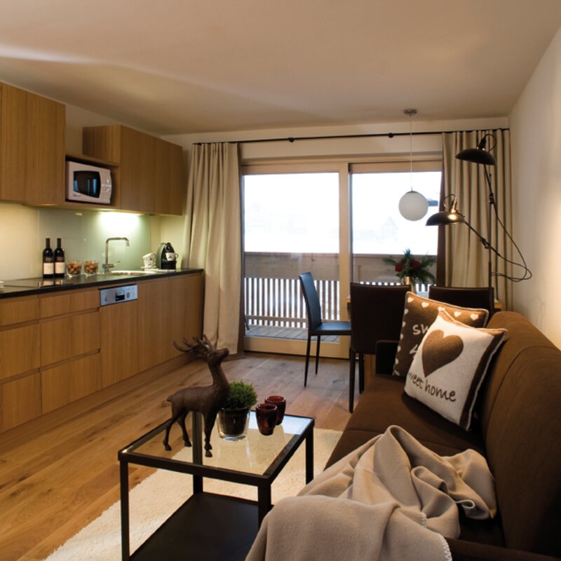 Küchenblock mit Nespresso Kaffee-Maschine, Mikrowelle, Geschirrspüler, Kühlschrank mit Tiefkühlfach, Gläser, Besteck, Geschirr.