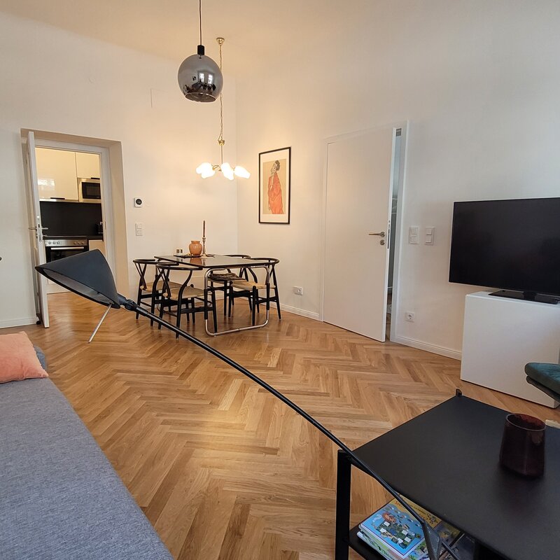 Helles Wohnzimmer mit Fischgrätparkett, Esstisch & TV – 2-Zimmer Wohnung, Kurzzeitmiete Wien, 1–6 Monate