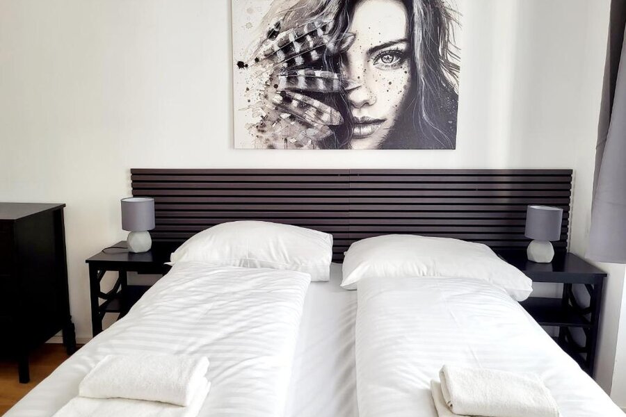 Helles Schlafzimmer mit Doppelbett & Wandkunst – 2-Zimmer-Wohnung, Kurzzeitmiete & Wohnen auf Zeit für 1 bis 6 Monate in Wien