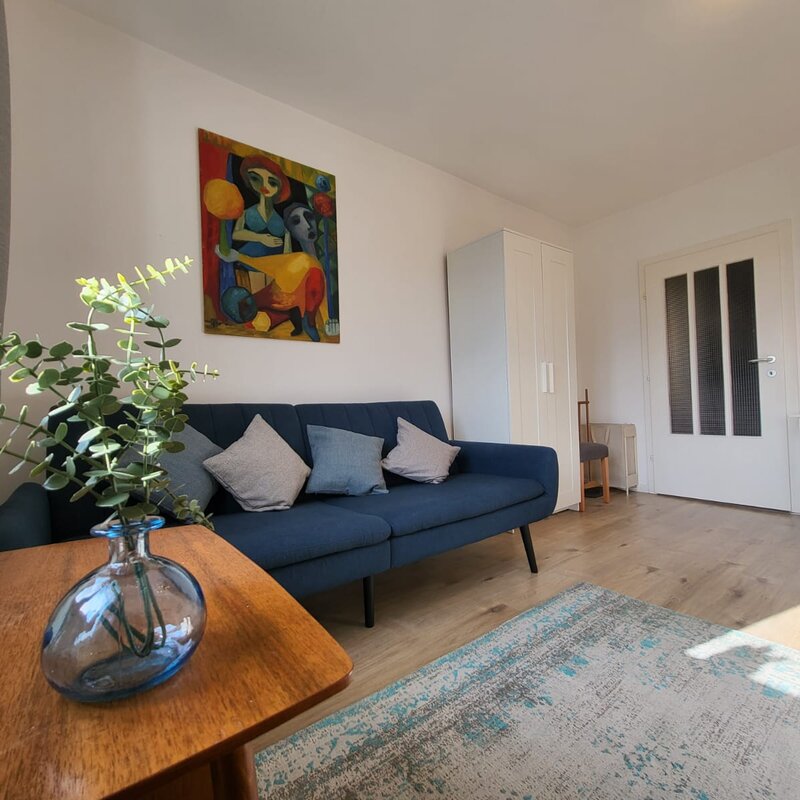Helles Wohnzimmer mit blauem Sofa & Kunstwerk – 2-Zimmer Wohnung, Kurzzeitmiete & Wohnen auf Zeit für 1 bis 6 Monate in Melk