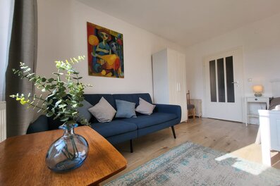 Helles Wohnzimmer mit blauem Sofa & Kunstwerk – 2-Zimmer Wohnung, Kurzzeitmiete & Wohnen auf Zeit für 1 bis 6 Monate in Melk