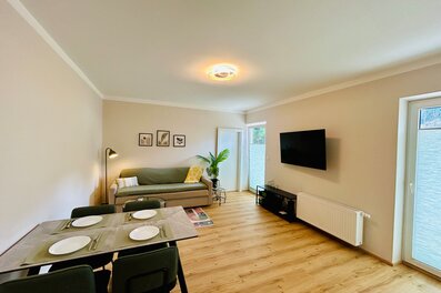 Helles Wohn-Esszimmer mit TV & Sofa – 2-Zimmer Wohnung zur Kurzzeitmiete in Hof bei Salzburg, 1–6 Monate