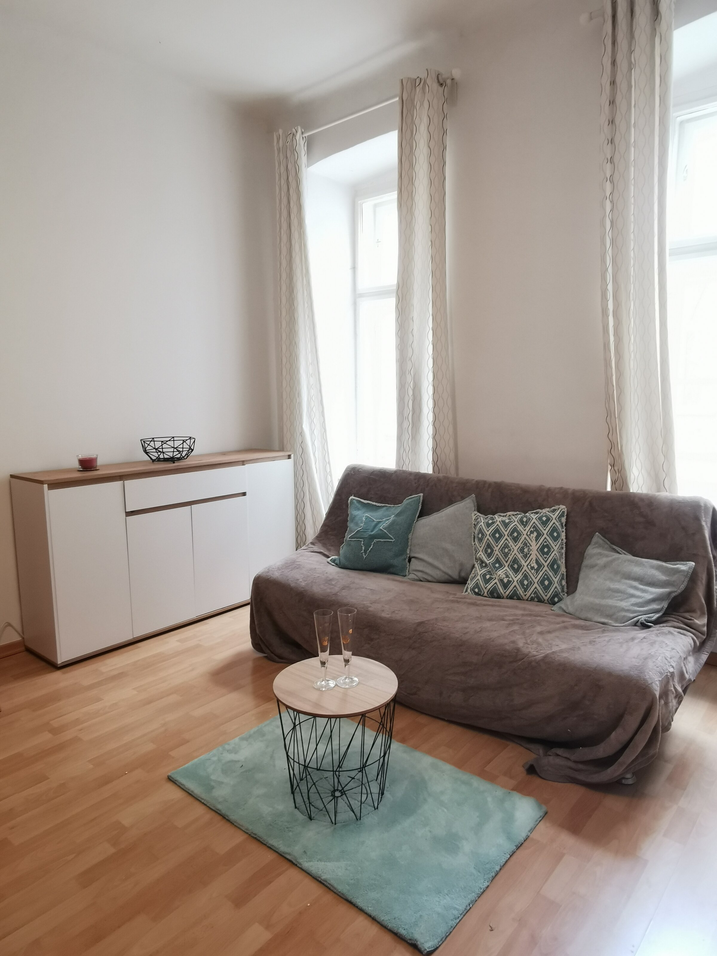Helles Wohnzimmer mit Sofa & modernem Sideboard – 1-Zimmer Apartment zur Kurzzeitmiete, Wohnen auf Zeit 1 bis 6 Monate, Wien