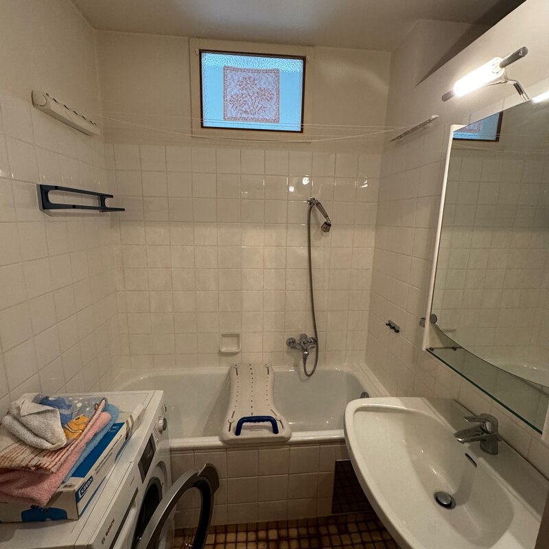 Das Badezimmer ist mit einer Badewanne mit Duschfunktion ausgestattet. Helle weiße Fliesen sorgen für eine freundliche Atmosphäre. Waschbecken mit Spiegel und Ablage für zusätzlichen Komfort. Auch eine Waschmaschine ist vorhanden | © Stefan Gabriel