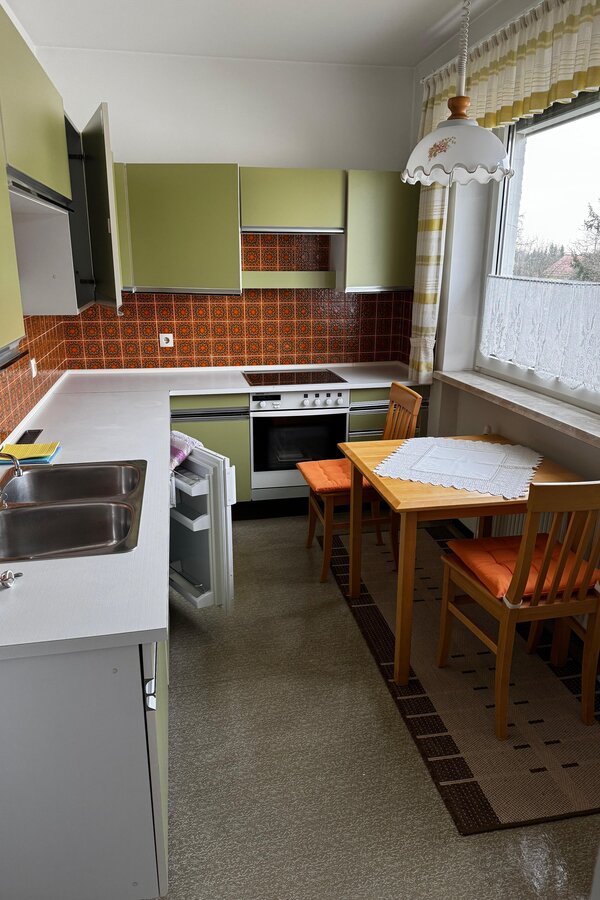 Die Küche ist voll ausgestattet und bietet ausreichend Arbeitsfläche. Der Essbereich mit Tisch und zwei Stühlen liegt direkt am Fenster und sorgt für eine helle, freundliche Atmosphäre. Die Einbauküche verfügt über Backofen, Herd, Spüle und Kühlschrank. Klassische Fliesen verleihen der Küche einen charmanten Retro-Stil. | © Stefan Gabriel