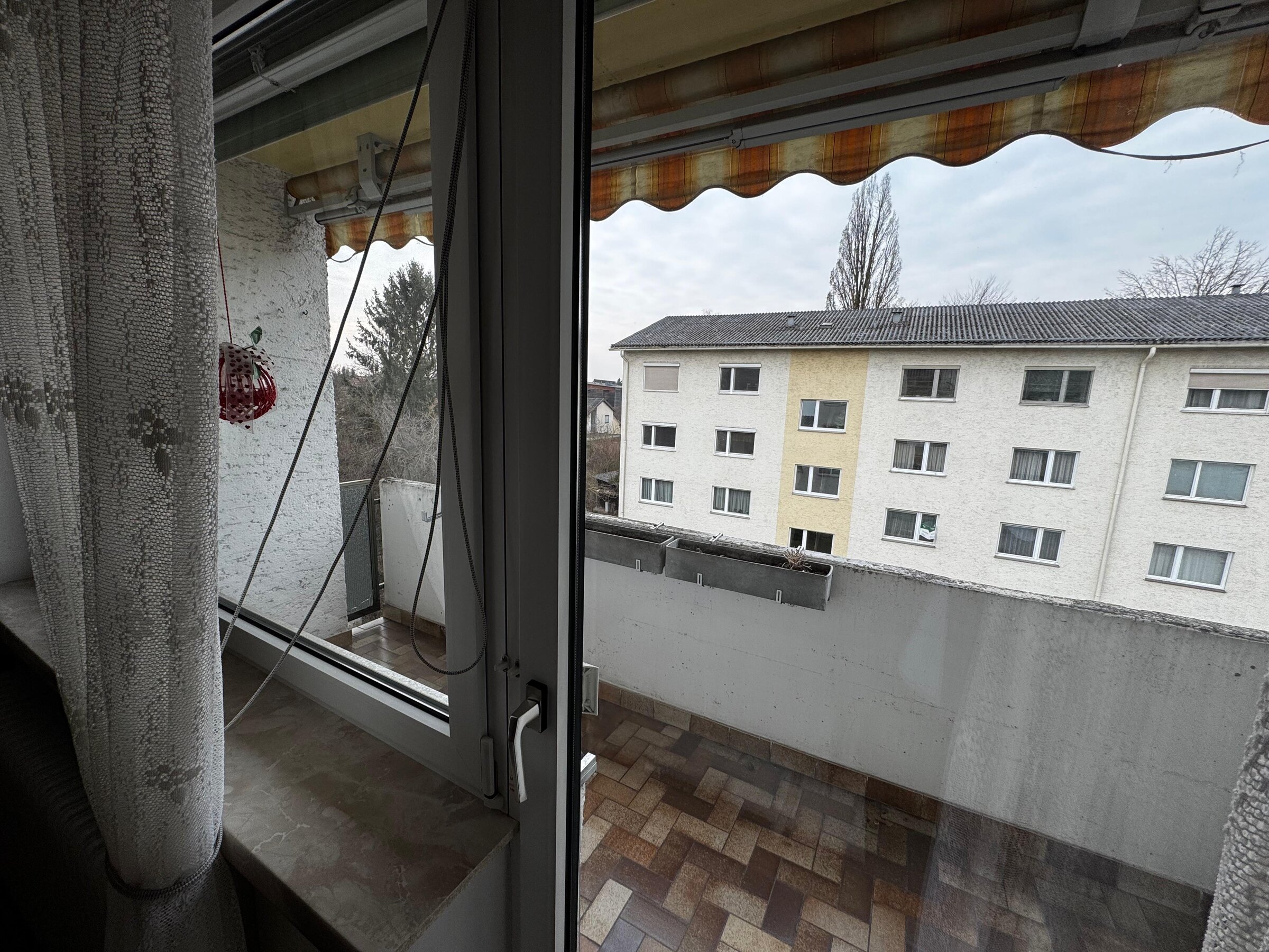 Die 6 m² große Loggia bietet einen schönen Ausblick auf die umliegenden Wohnhäuser und Grünflächen. Große Fenster lassen viel Tageslicht in die Wohnung. Ein Sonnenschutz-Markise sorgt für angenehmen Schatten an heißen Tagen. Die Loggia ist ideal zum Entspannen und bietet zusätzlichen Wohnraum im Freien. | © Stefan Gabriel