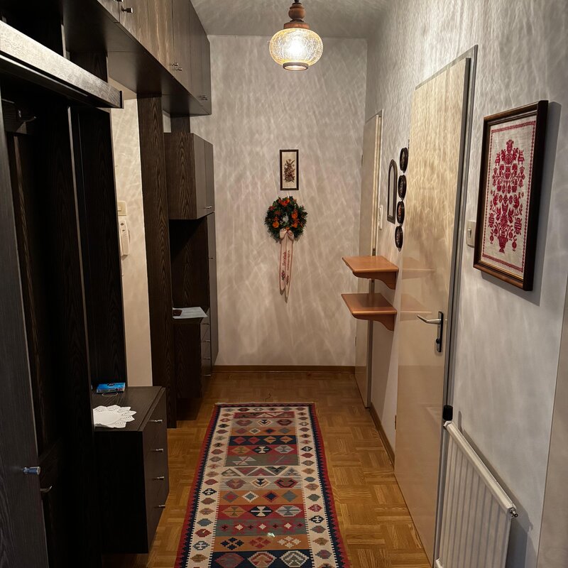 Der Vorraum bietet eine praktische Garderobe mit Ablagemöglichkeiten und ausreichend Platz für Jacken und Schuhe. Die Wanddekoration und der Teppich verleihen dem Eingangsbereich eine gemütliche Atmosphäre. Von hier aus gelangt man in die weiteren Räume der Wohnung. | © Stefan Gabriel