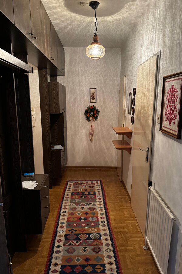 Der Vorraum bietet eine praktische Garderobe mit Ablagemöglichkeiten und ausreichend Platz für Jacken und Schuhe. Die Wanddekoration und der Teppich verleihen dem Eingangsbereich eine gemütliche Atmosphäre. Von hier aus gelangt man in die weiteren Räume der Wohnung. | © Stefan Gabriel