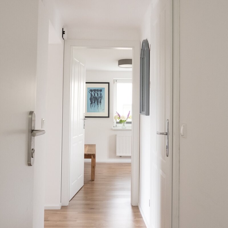The cloakroom is located directly behind the entrance door. To the left is the open-plan living and dining area, straight ahead is the bedroom, and to the right is the modern bathroom.