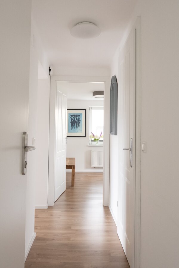 The cloakroom is located directly behind the entrance door. To the left is the open-plan living and dining area, straight ahead is the bedroom, and to the right is the modern bathroom.