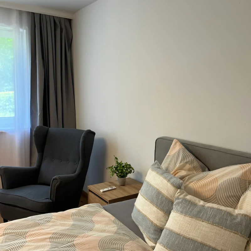 Bett mit Nachtkästchen und Ohrensessel